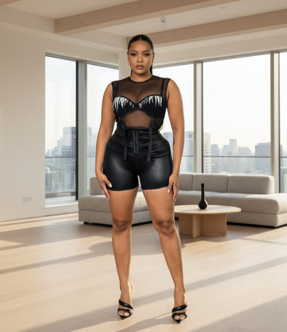 A person wearing black corset waist shorts that reach mid-thigh, paired with a black crop top.