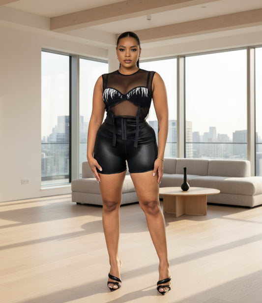 A person wearing black corset waist shorts that reach mid-thigh, paired with a black crop top.